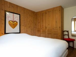 Un dormitorio con una cama blanca y una silla roja. en Apartment Hyacinthe 14 by Interhome, en Villars-sur-Ollon