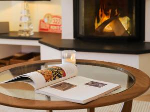 un libro y una vela sobre una mesa de cristal con chimenea en Apartment Les Cîmes by Interhome, en Gryon