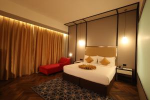 a hotel room with a bed and a red chair at Hotel Polo Towers Agartala in Agartala