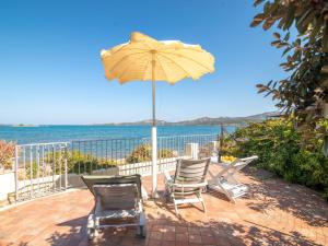 un patio con sedie e un ombrellone e l'oceano di Apartment Donatella by Interhome a Cannigione