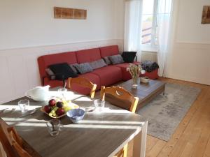 a living room with a table and a red couch at Apartment Grand-Rue 143 by Interhome in Auberson