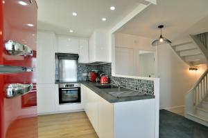 a kitchen with white cabinets and a sink at Le Gîte du Château - Duplex en centre-ville in Dinan +7 photos