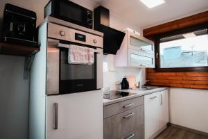 a kitchen with white cabinets and black appliances at Jacuzzi, Sauna, Garten, Terrasse, Grill, 6 Personen, Moselstaustufe, Netflix, Sky, Smart TV in Neef