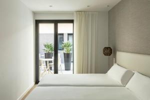1 dormitorio con cama blanca y balcón en Europa Apartments, en Hospitalet de Llobregat