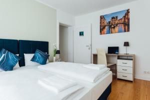a bedroom with a large bed with blue pillows and a desk at Hanseat Apartments in Hamburg