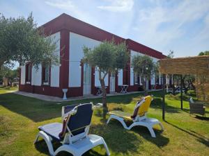 two chairs sitting in the grass in front of a building at Il Casale di Punta Prosciutto in Punta Prosciutto