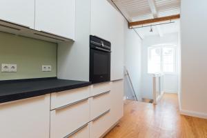 a kitchen with white cabinets and a black appliance at Hanseat Apartments in Hamburg