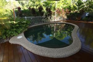 uma piscina com um assento de pedra num deque de madeira em 1 Bed Apartment Close to the Beach and Town em Port Douglas