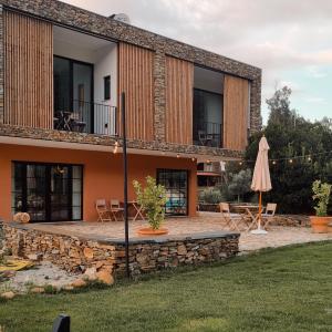 an external view of a house with a patio and an umbrella at Quinta das Levadas - Country House & Nature in Alvoco das Várzeas