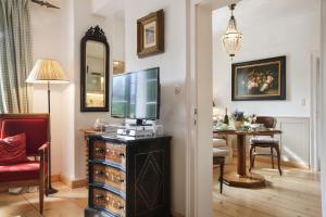 a living room with a television on a dresser with a table at Garden Cottage der Villa Liechtenstein in Altaussee