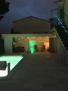 un patio trasero por la noche con piscina y luces en La Coccinelle en Nimes