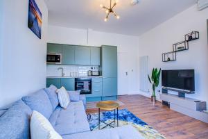 a living room with a blue couch and a kitchen at 132 Qweens Stay in Southend-on-Sea