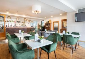 ein Restaurant mit grünen Stühlen und Tischen und einer Bar in der Unterkunft Hotel Troja in Prag