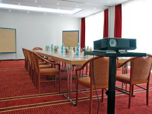 a conference room with a table with chairs and a television at Morada Hotel Gifhorn in Gifhorn