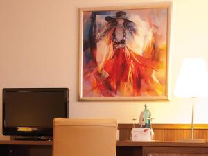 a painting of a woman on a wall with a television at Morada Hotel Gifhorn in Gifhorn