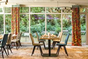 jadalnia ze stołami i krzesłami oraz dużym oknem w obiekcie Morada Hotel Gifhorn w mieście Gifhorn