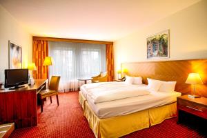 a hotel room with a bed and a desk and a television at Morada Hotel Gifhorn in Gifhorn