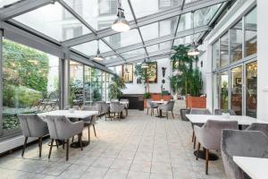 ein Restaurant mit Tischen, Stühlen und Fenstern in der Unterkunft Hotel Troja in Prag