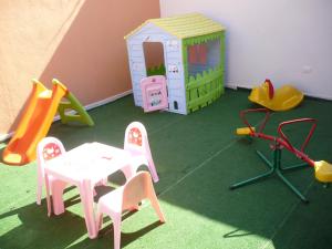 una sala giochi con tavolo e sedie e una casetta per i giochi di Rosa Hotel a Capoterra