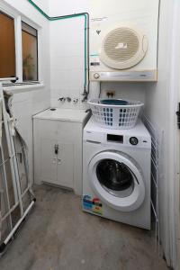 uma lavandaria com uma máquina de lavar roupa e um lavatório em 1 Bed Apartment Close to the Beach and Town em Port Douglas