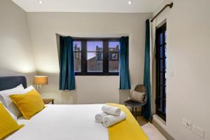 ein Schlafzimmer mit einem Bett mit gelben Kissen und einem Fenster in der Unterkunft 2 Bed Lux Apartments near Central London FREE WIFI by City Stay Aparts London in London