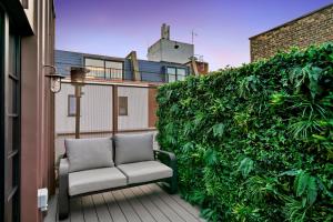 un sofá en un balcón con un seto verde en 2 Bed Lux Apartments near Central London FREE WIFI by City Stay Aparts London, en Londres
