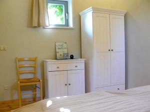 ein Schlafzimmer mit einem Bett, einem Schrank und einem Stuhl in der Unterkunft Ferienwohnung Zur Alten Böttcherei in Kröslin