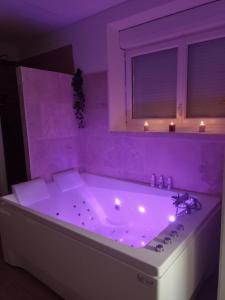 a purple bathroom with a tub with lights in it at Bulles de Lune in Sacy