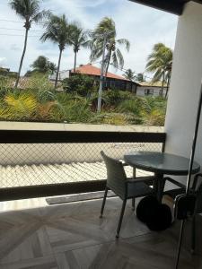 uma varanda com mesa, cadeiras e palmeiras em Samba Villa da Praia em Salvador