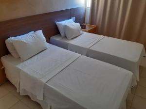 duas camas num quarto de hotel com lençóis e almofadas brancas em Samba Villa da Praia em Salvador