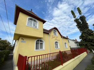 una casa amarilla con una valla roja en Kiskut Liget Pension, en Győr