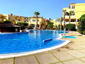 a large blue swimming pool with palm trees and buildings at Duquesa del Mar in San Miguel de Abona