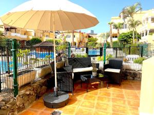 a patio with a table and an umbrella and chairs at Duquesa del Mar in San Miguel de Abona