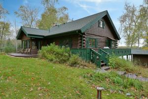 Cabaña de madera con techo verde y patio en Birch Haven home, en Clam Lake