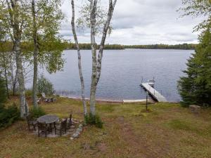 uitzicht op een meer met een tafel en stoelen bij Birch Haven home in Clam Lake