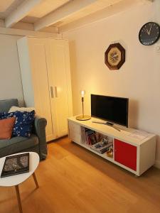 uma sala de estar com uma televisão, um sofá e um relógio em Mimi Gallery em Budapeste