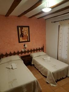 GodojosにあるCASA RURAL LA SOLANAのベッドが2つあり、壁に絵が飾られている寝室