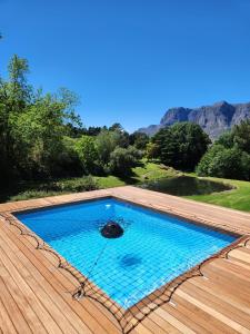 een zwembad op een houten terras met bergen op de achtergrond bij Wechmarshof in Stellenbosch