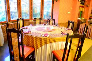 einen Esstisch mit einem weißen Tischtuch und Stühlen in der Unterkunft Hotel Migmar in Thimphu