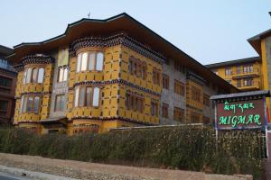 un bâtiment jaune avec un panneau devant lui dans l'établissement Hotel Migmar, à Thimphou