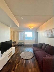 ein Wohnzimmer mit einem Sofa und einem Flachbild-TV in der Unterkunft Kotimaailma - Premium 2 bedroom apartment with Terrace & Sauna in Vantaa