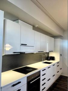 a kitchen with white cabinets and a sink at Kotimaailma - Premium 2 bedroom apartment with Terrace & Sauna in Vantaa