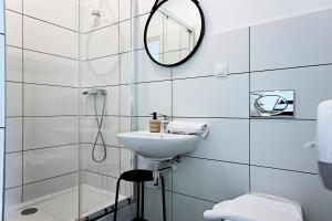 ein weißes Badezimmer mit einem Waschbecken und einem Spiegel in der Unterkunft Folk Deluxe in Lublin