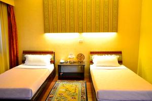 a room with two beds and a table between them at Hotel Migmar in Thimphu