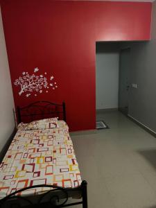 1 dormitorio con cama y pared roja en Tani s Homestay en Bāruipur