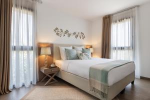 a bedroom with a large white bed and windows at Résidence Pierre & Vacances Premium Domaine du Golfe du Lion in Saint-Cyprien