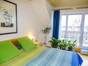 City-Dachapartment Mainz في ماينز: غرفة نوم بسرير ومخدات خضراء ونباتات