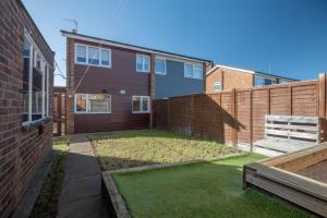 a backyard with a fence and a yard with grass at Stunning and Modern House - Perfect for Families in Bedford