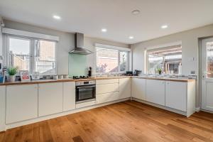 una cocina vacía con armarios blancos y ventanas en Stunning and Modern House - Perfect for Families, en Bedford