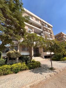 un edificio de apartamentos con un árbol delante de él en Cozy holiday apartment in Maadi, en El Cairo